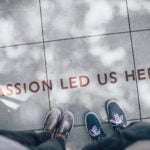 Feet on sidewalk, with words "passion led us here"